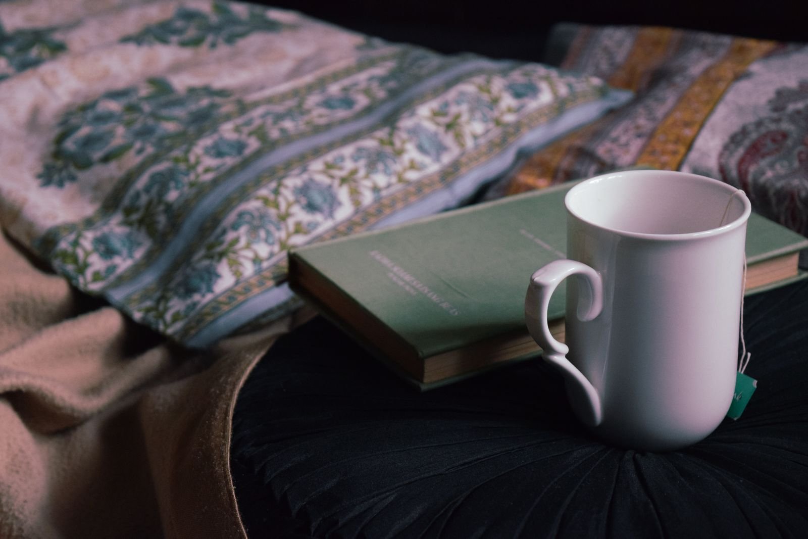 Xícara de chá e livro fechado sobre a cama, rotina calma antes de dormir sem telas